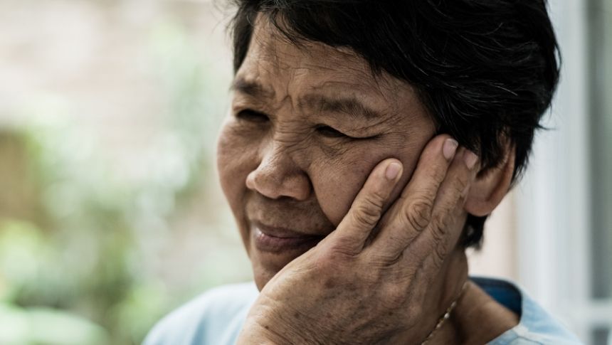 Image of a person clutching their jaw in pain Massage therapy for TMJ pain